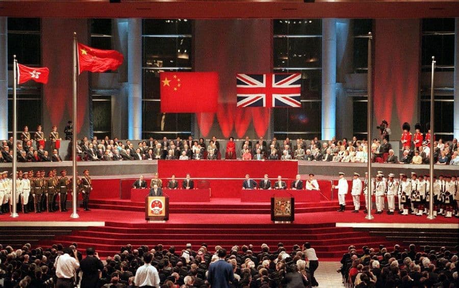 The joint handover ceremony at the Hong Kong Convention and Exhibition Centre, 1 July 1997, at which sovereignty over Hong Kong was transferred from the United Kingdom to the People's Republic of China. The Chinese national flag and the Union Jack are displayed side by side as dignitaries from both countries attend the formal proceedings.